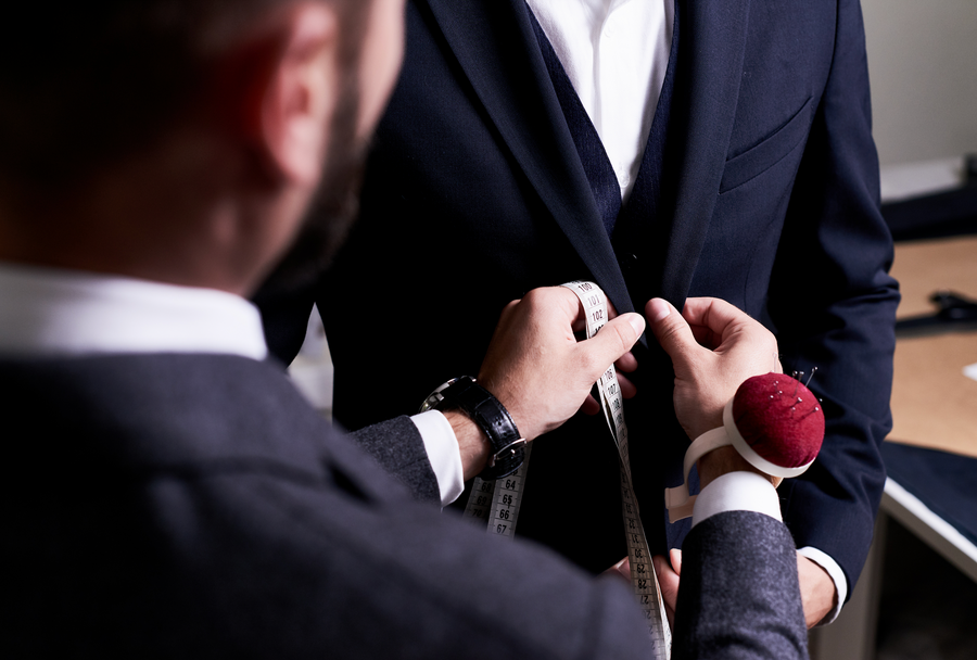 Tailor measuring a suit jacket with a tape measure