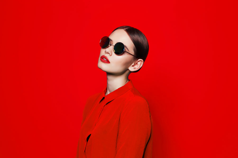 Woman wearing sunglasses and a red outfit against a red background