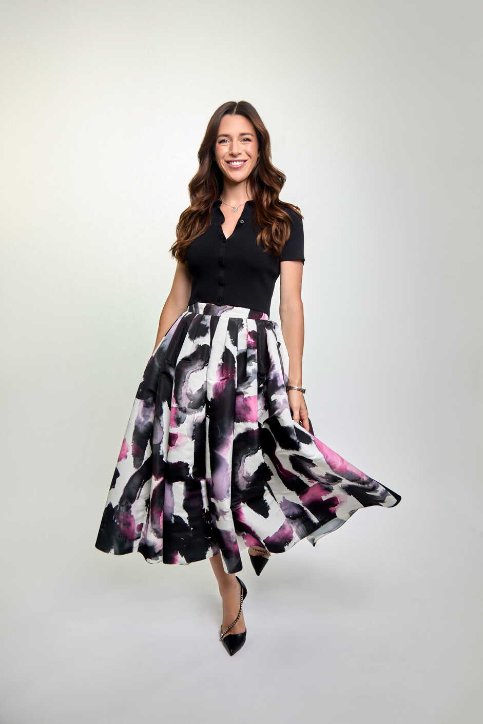 Woman wearing a black top and floral skirt on a white background