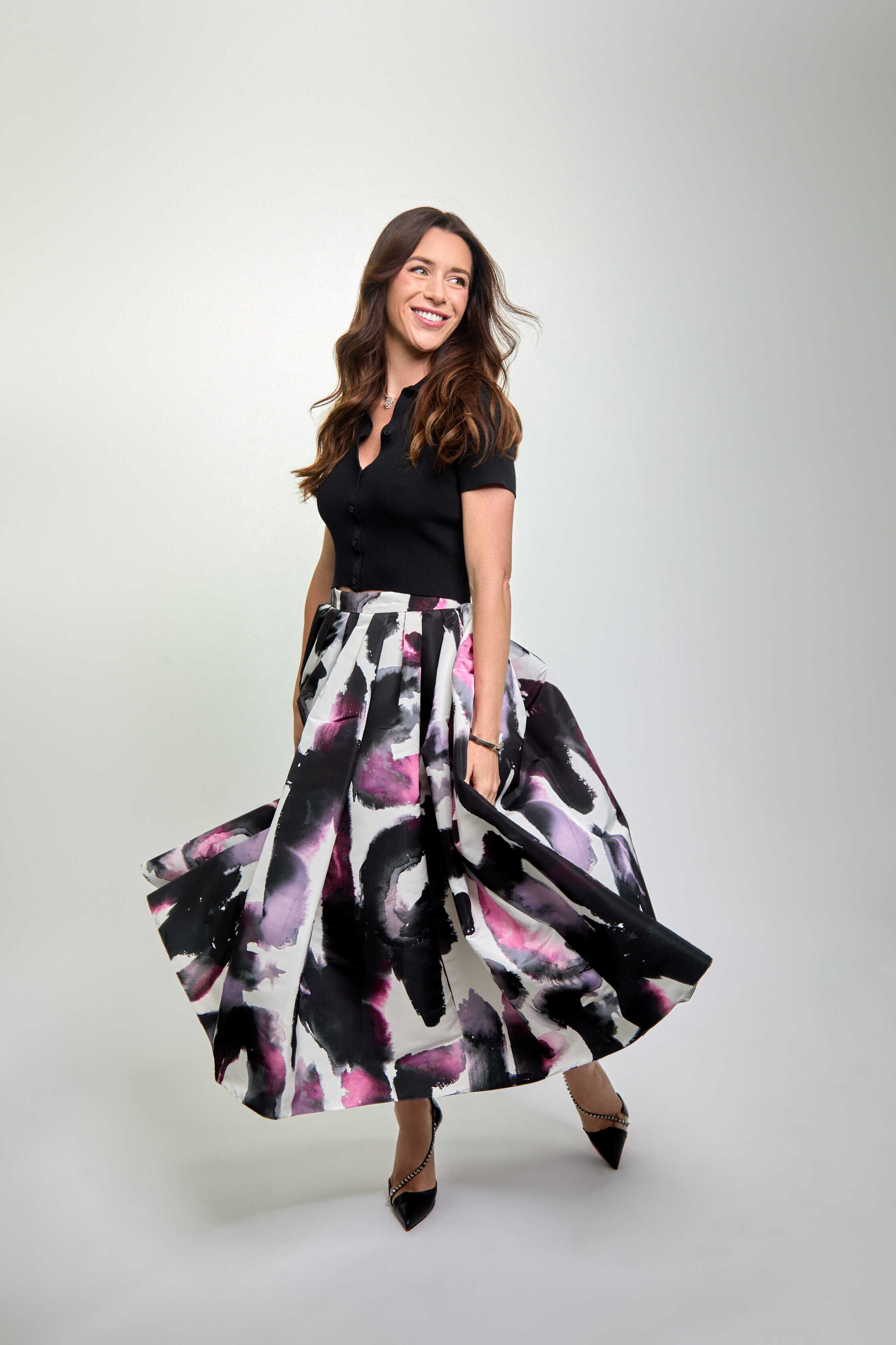 Woman wearing a black top and colorful skirt on a white background