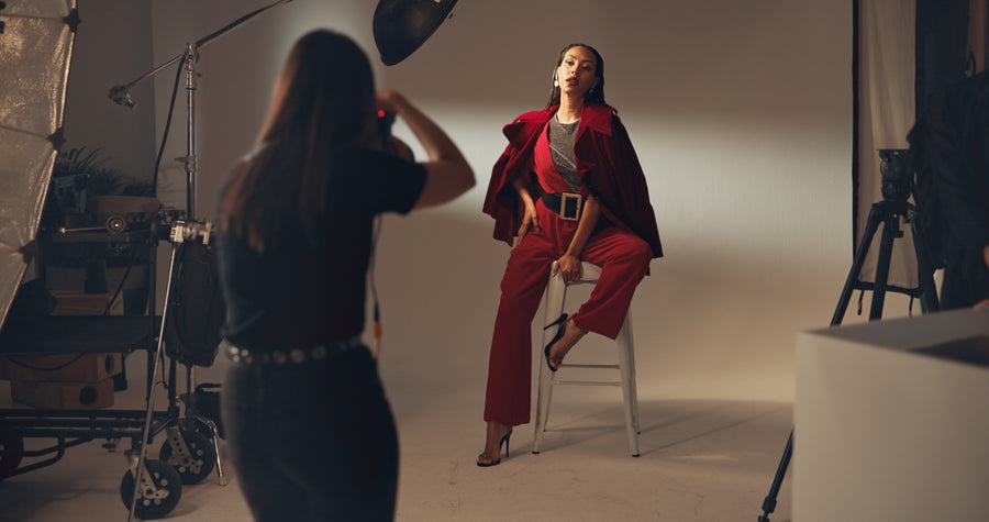 Photographer taking a picture of a model in a red outfit in a studio setting.